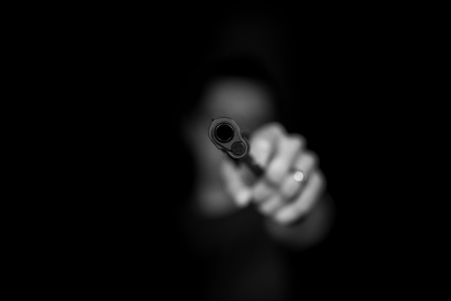 Man aims with a gun from the shadows