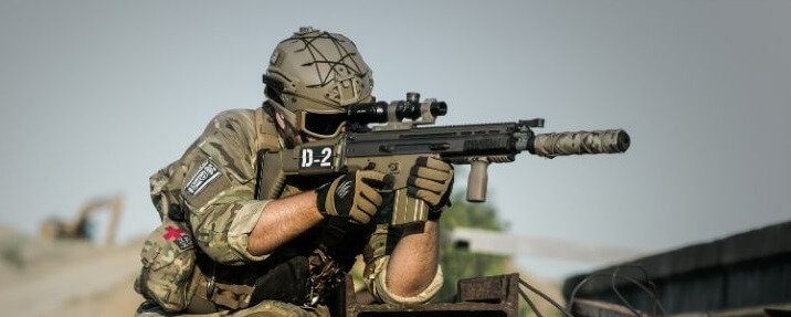 A soldier carrying a suppressed tactical gun